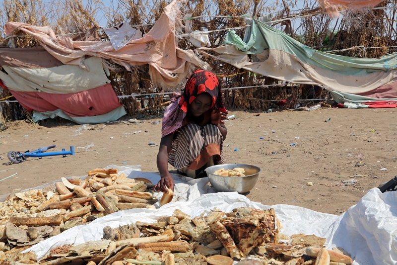 فتاة يمنية فقيرة تبحث في القمامة عن قصاصات خبز تحفظ بها رمق عائلتها